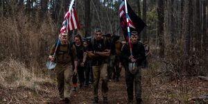 Ruckers hiking with flags during GORUCK BRAGG Heavy at Fort Bragg