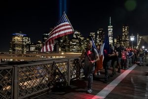 GORUCK New York 9/11 25th Anniversary City Ruck Weekend - marchers with flags and NYC skyline at night