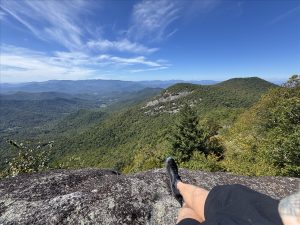 Runner on a bare rock overlook above forested Appalachian ridges