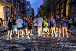 Bridge Runners crew on a cobblestone street in lower Manhattan at dusk