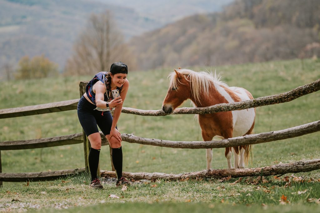 Runner pausing at a fence beside one of the wild ponies of Grayson Highlands