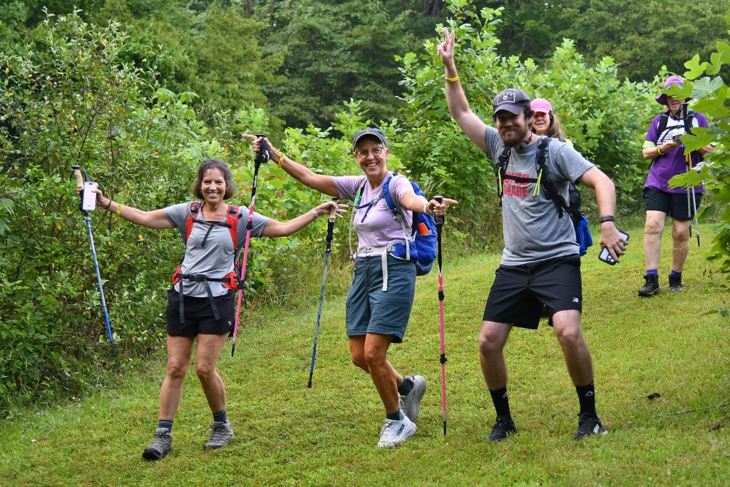 Hikers with backpacks and trekking poles celebrating on a grassy trail at Mammoth March Southeast Ohio