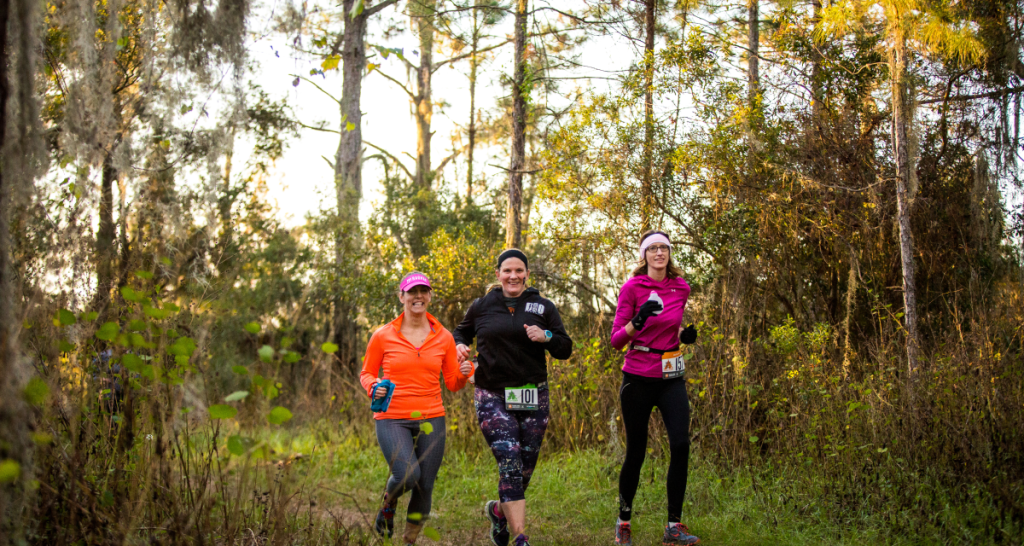 Runners on a shaded forest trail at Ragnar Trail Florida