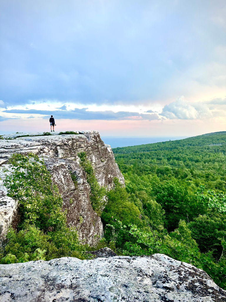 Runner standing on a cliff ledge above the green Shawangunk valley at Squatchywaska Mountainfest