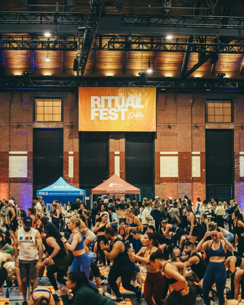 A packed hall of people mid-workout under a RITUAL FEST screen at SoWa Power Station in Boston