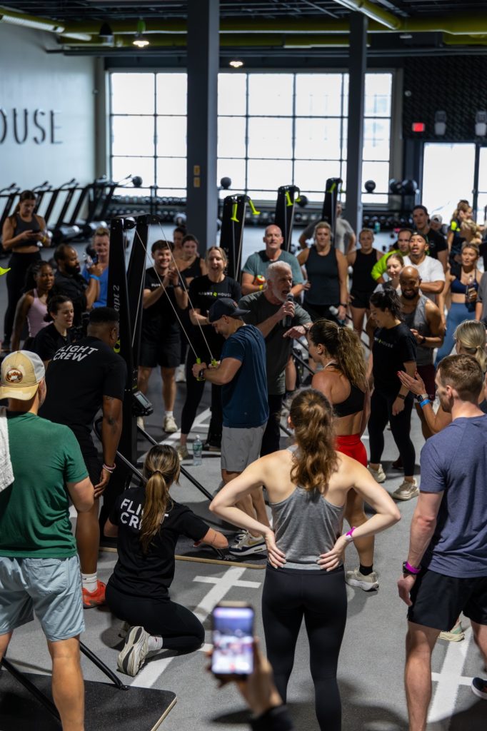 A large group gathered on the training floor for a briefing at Flight House Fitness